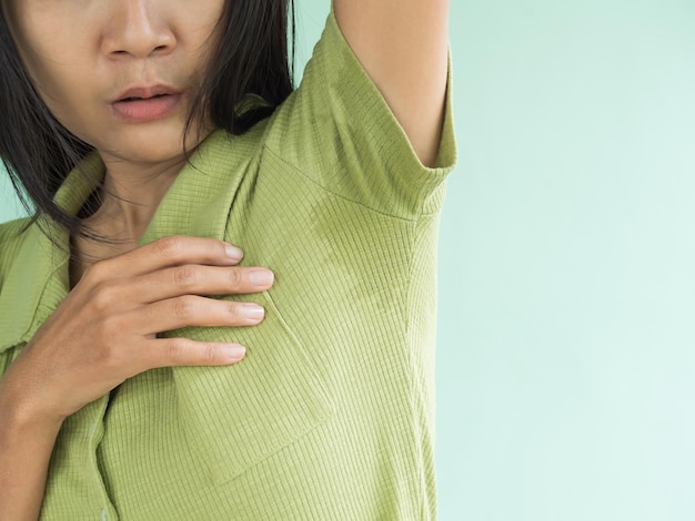 Woman Hyperhidrosis wet blue shirt underarm hand close up problem Armpit sweat stains and strong body odor hyperhidrosis sweatinghygiene for good health concept sweaty under arm