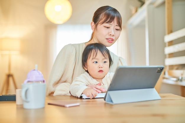 A woman and an infant who operate a tablet PC with a tired expression