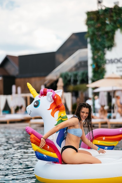 Woman on inflatable unicorn toy mattress float in pool