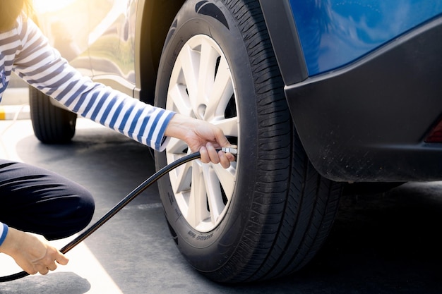 Woman inflates the tire Woman checking tire pressure and pumping air into the tire of car wheel Car