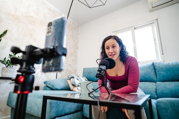 Woman influencer filming with her cell phone in her living room