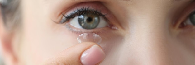 A woman inserts a contact lens into her eye face closeup eye diseases myopia and astigmatism