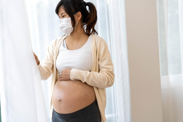 The woman is 28 weeks pregnant wearing a face mask to prevent viruses and pollen or pm25 dust