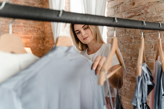 Woman is browsing through her various outfits hanging on the clothing rack in her wardrobe