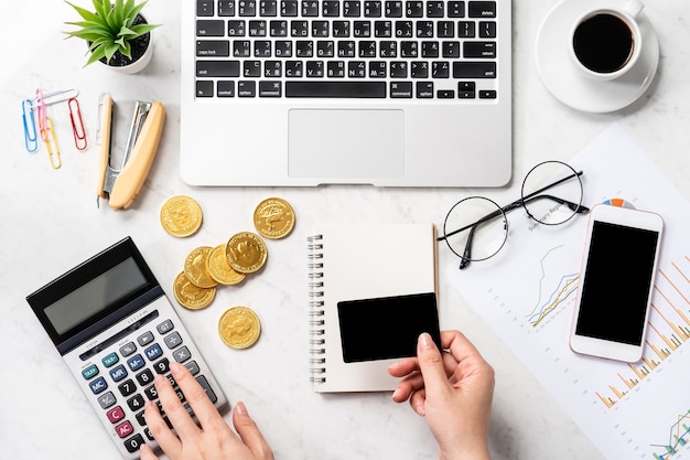 A woman is calculating the fee, profit and doing a payment online on a modern marble office table, mock up, top view, copy space, flat lay