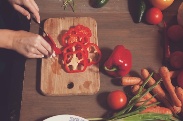 Woman is cutting a red pepper into rings