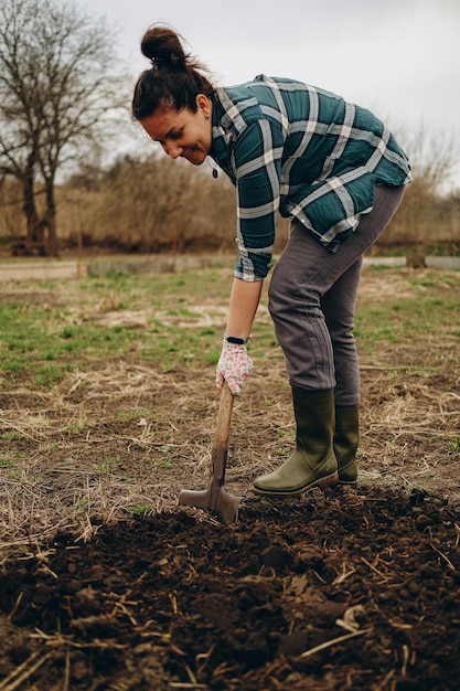 A woman is digging the earth in a field Agricultural work in the spring in the field Preparing the land for planting sheep in the spring