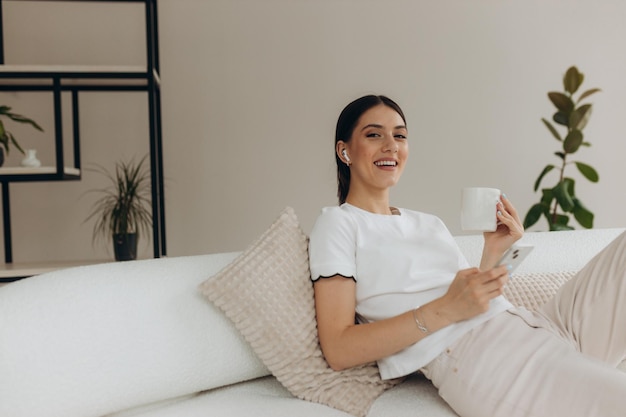 A woman is drinking coffee and using on a cell phone at home