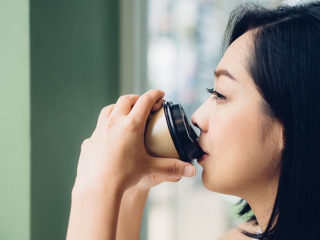 Woman is drinking hot cup of coffee in the cafe.