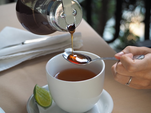 Woman is drinking tea with honey in a restaurant