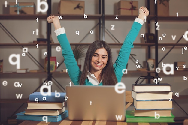 Woman is happy about her successful work with laptop at the table