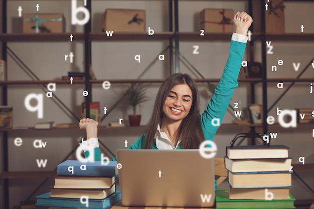 Woman is happy about her successful work with laptop at the wood table