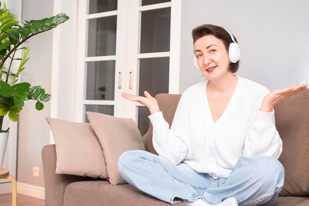 The woman is in headphone is listening and smiling to camera