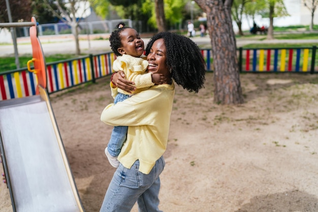 A woman is holding a baby in a park