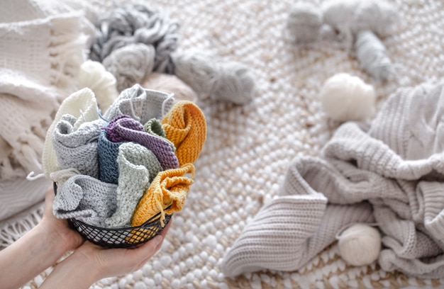 A woman is holding a basket with colored yarn .