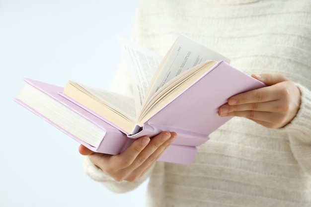 A woman is holding a book on a light background