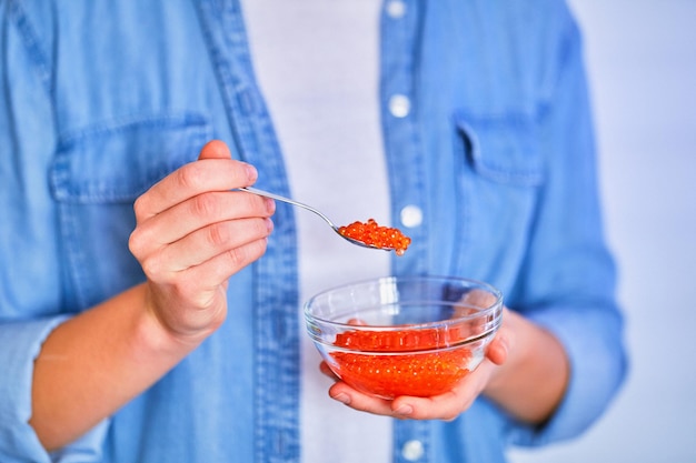 A woman is holding a bowl of red paprika.