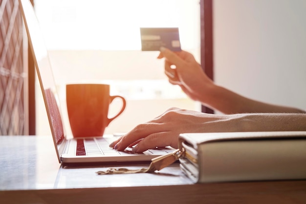 Woman is holding credit card and using laptop computer