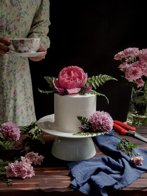 A woman is holding a cup and a cake with a flower on it.