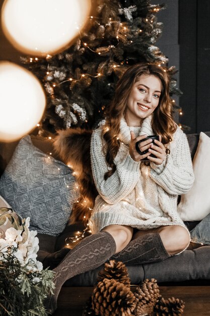 Woman is holding a cup of coffee and smiling.