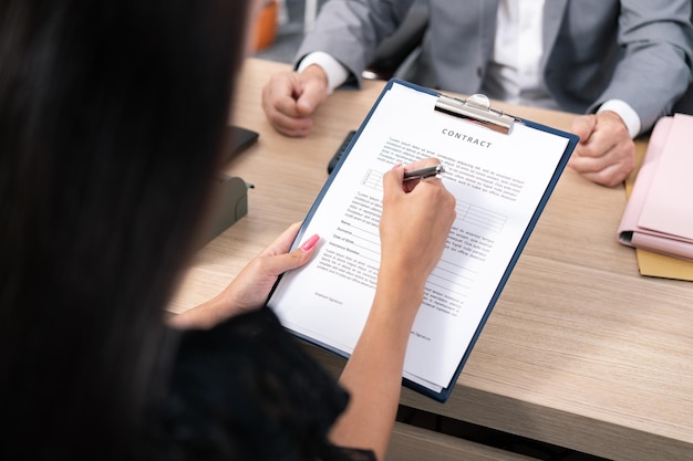 The woman is holding in hands an employment contract which she got from a mature older boss