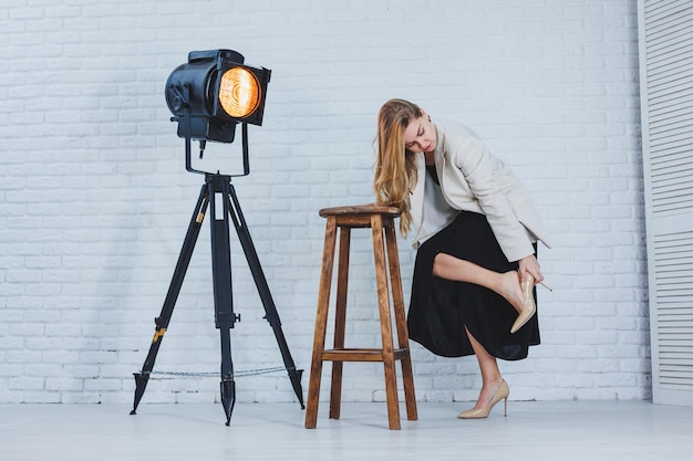 A woman is holding her leg she is wearing high heeled shoes and her legs hurt The woman is wearing a black dress and beige high heel shoes Leg pain from high heels