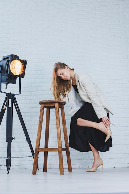 A woman is holding her leg she is wearing high heeled shoes and her legs hurt The woman is wearing a black dress and beige high heel shoes Leg pain from high heels