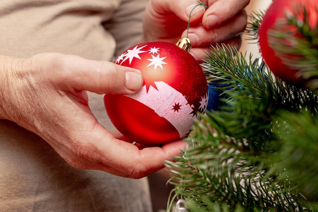 A woman is holding a New Year's toy a ball in her hands which decorates the Christmas tree