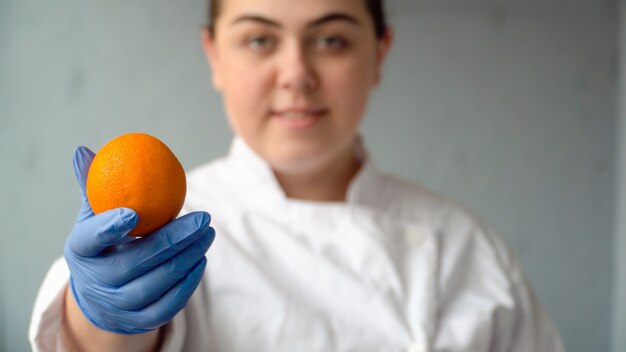 The woman is holding an orange in her hand