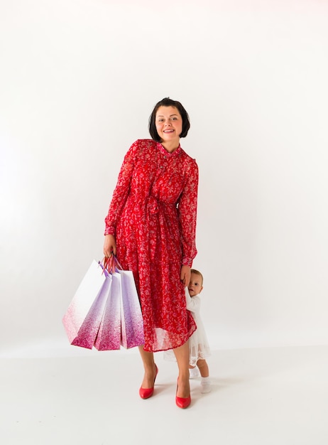 Woman is holding packages. Mom and little child are shopping. White background. Black Friday.