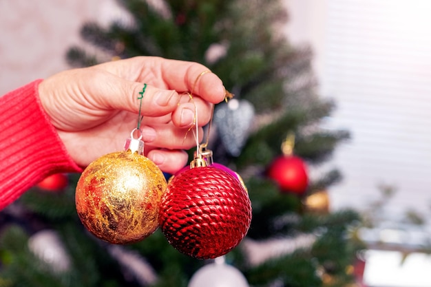 A woman is holding toys for decorating a Christmas tree