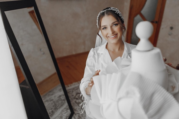 A woman is holding a white dress in front of a mirror