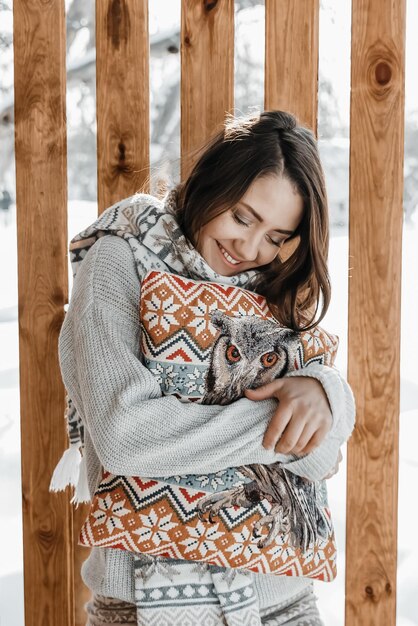 Woman is hugging a pillow at the terrace at winter.