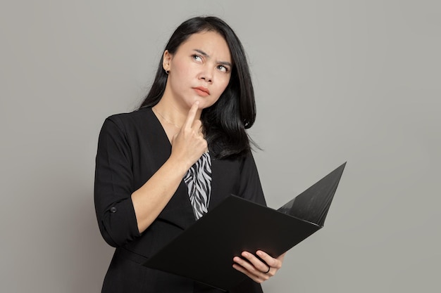 Woman is imagining looking for an idea with her index finger on the chin while holding a folder