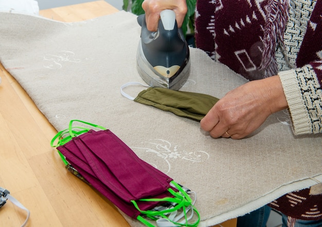 A woman is ironing covid mask