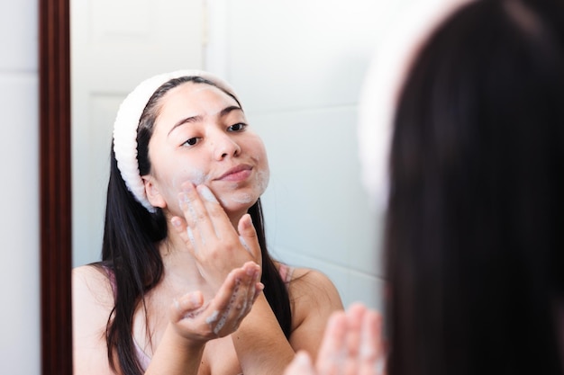 A woman is looking in the mirror and applying a dry face.