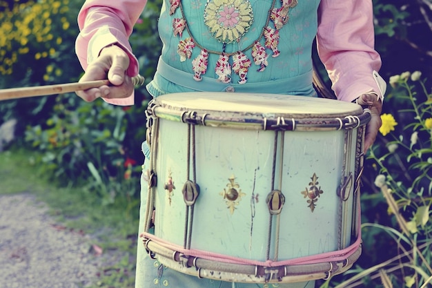 a woman is playing a drum with a blue shirt on