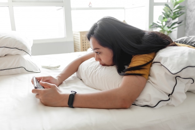 Woman is playing mobile game in her bedroom in concept stay at home.