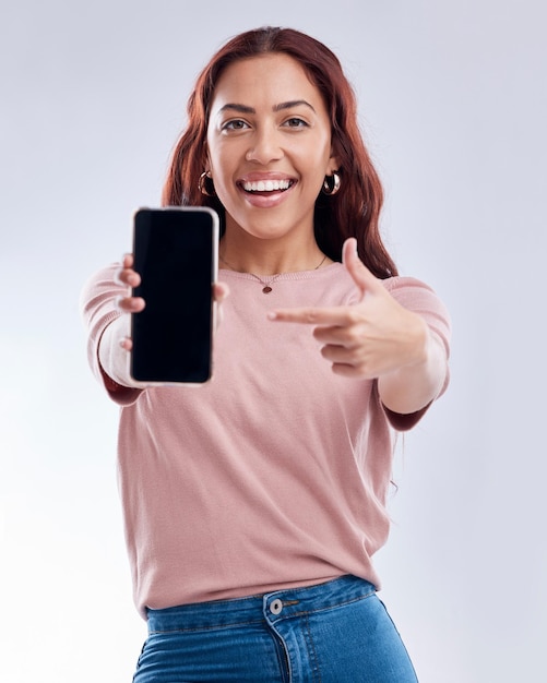 Woman is pointing at phone screen mockup and advertising mobile app ads on white background Website promo marketing and female brand ambassador in portrait with social media branding in studio