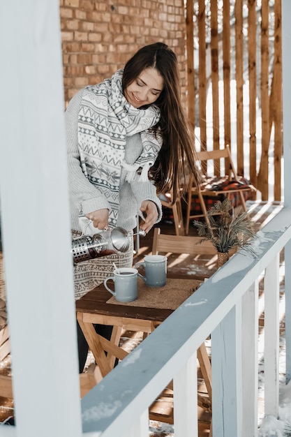 Woman is pouring tea at the terrace during winter.