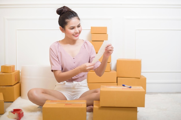 A woman is preparing products with cardboard boxes for shipping.