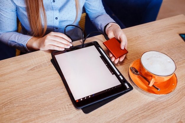 Woman is preparing to work on her tablet using external hard drive cup of coffee on the table