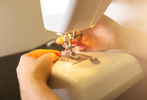 Woman is putting thread in sewing machine Girls hands at freelance work Fashion concept Creating of new clothes process Hobby ideas