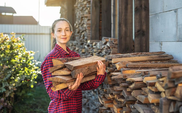 Woman is putting wood in hands from a woodpile for a home fireplace Woodburning heating and the energy crisis