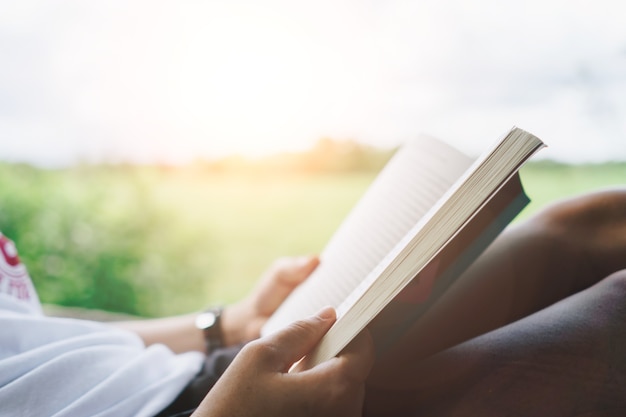 Woman is reading book in beautiful park and pond relax and peaceful environment background.