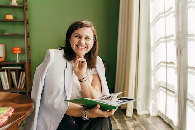 A woman is reading flipping through a novelette book in an apartment Happy mood stylish confident