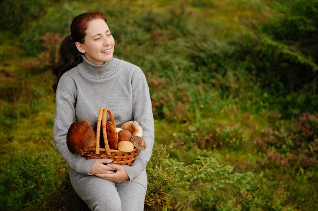 Woman is resting in a green forest with bascket of mushrooms concept of ecotourism