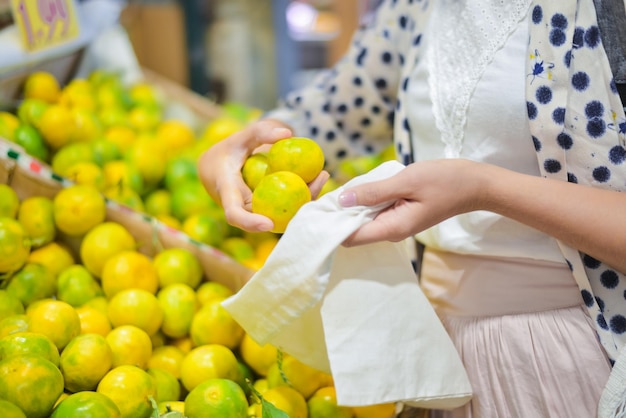 woman is selecting fruits in cotton bag at local food market z