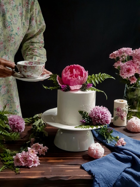 A woman is serving a cake with a cup of tea and a flower on it.