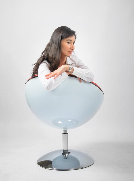 A woman is sitting in a chair with her legs crossed and wearing glasses